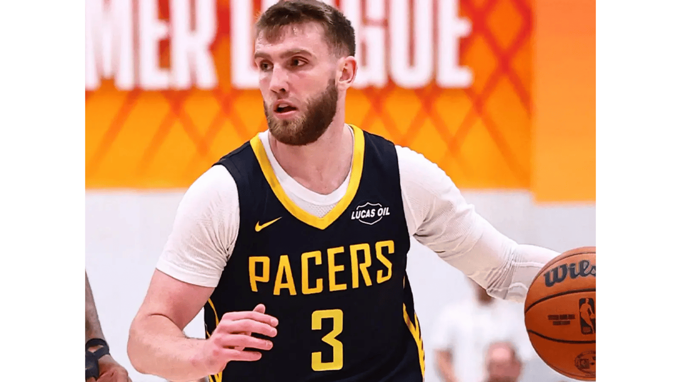Purdue product Braden Smith drives upcourt in a navy Indiana Pacers Summer League jersey, number 3, in front of an orange NBA Summer League backdrop in Las Vegas.