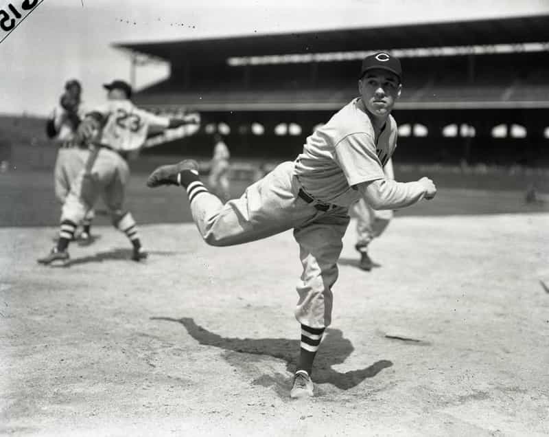 Vintage black-and-white photo of a baseball pitcher in a Cleveland uniform following through on a pitch at a packed ballpark.