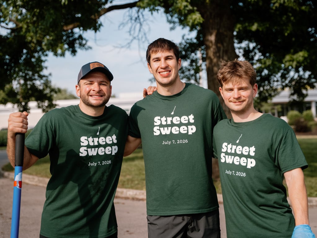Three volunteers in Street Sweep tees, one holding a push broom