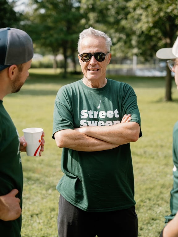 A longtime volunteer in a Street Sweep tee talking with the crew