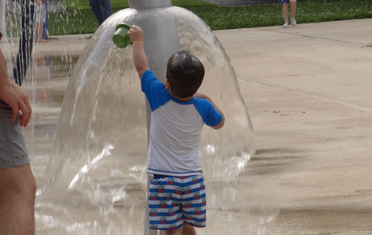 A child playing at a neighborhood splash pad on a District Church outing