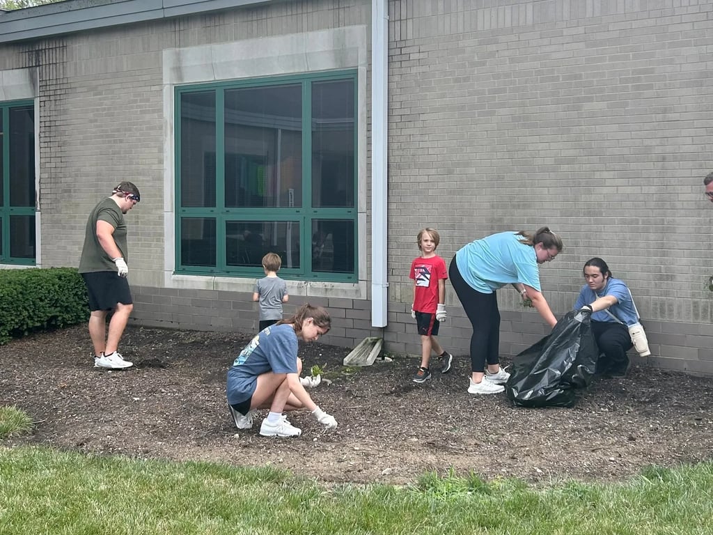 Volunteers from The District Church weeding and clearing a landscaped bed at a neighborhood school