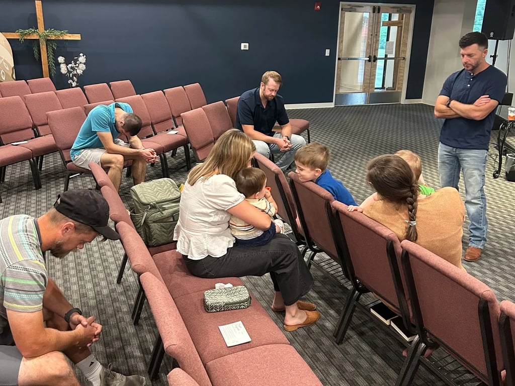 Members of The District Church praying together in the seats after a Sunday gathering