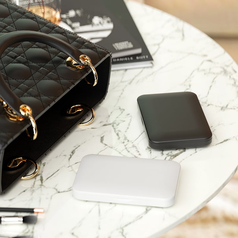 The folding compact mirror in black and in white, next to a handbag