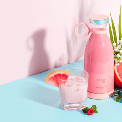Portable blender with fruit on a pink background
