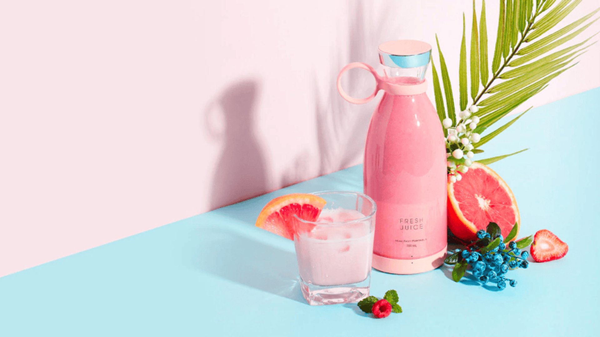 Portable blender with fruit on a pink background