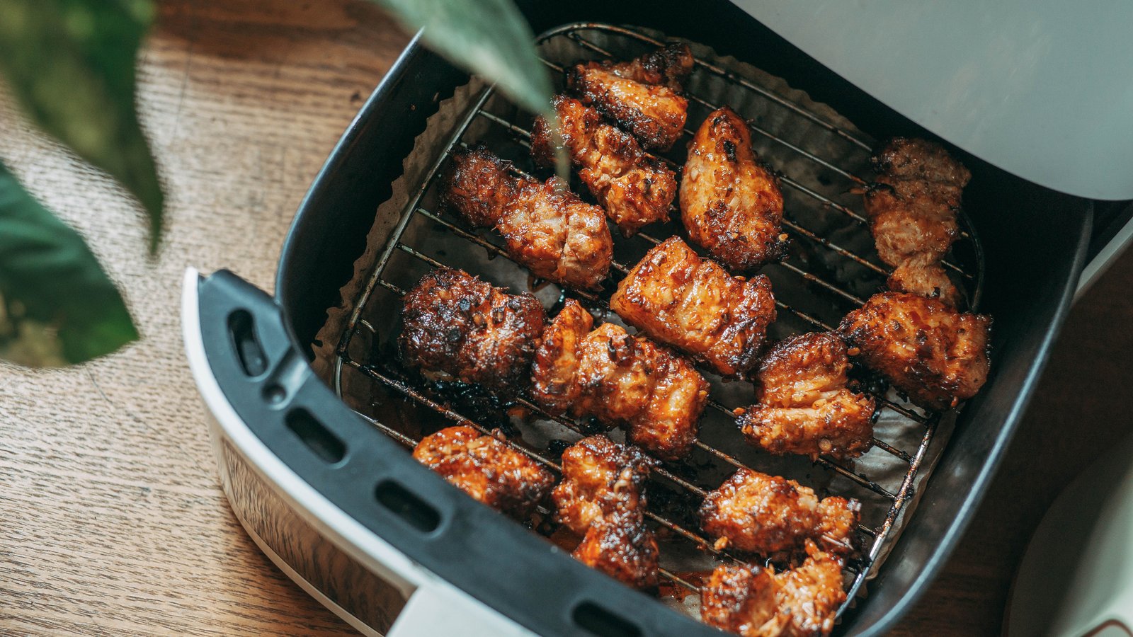 Compact air fryer on a kitchen counter with a basket of crisped food