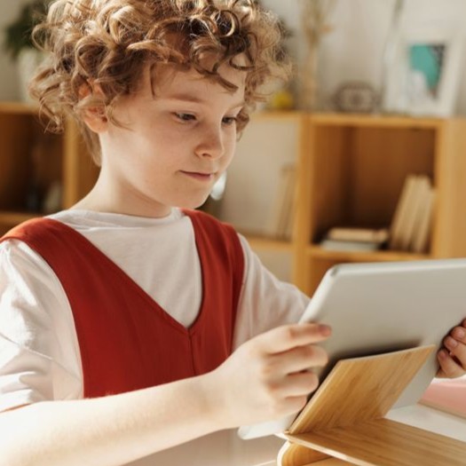 Uczeń robiący odręczne notatki rysikiem na tablecie w szkolnej ławce