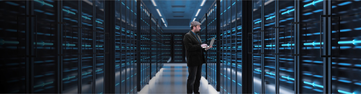 An IT professional uses a laptop to manage servers in a network room.