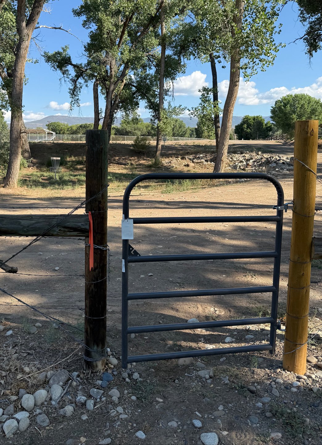 The gate to get through the fence on hole 13. The short and long baskets of hole 13 are in the background.
