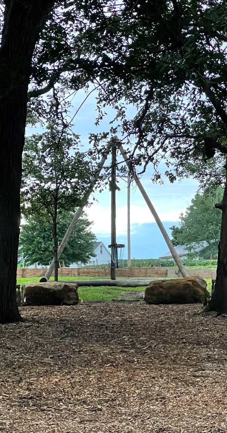 Hole 20 - “Happy Ending” - Green. Tipi hanging basket. Forced carry must carry rocks, surrounded by hazard outside wood walls. 
