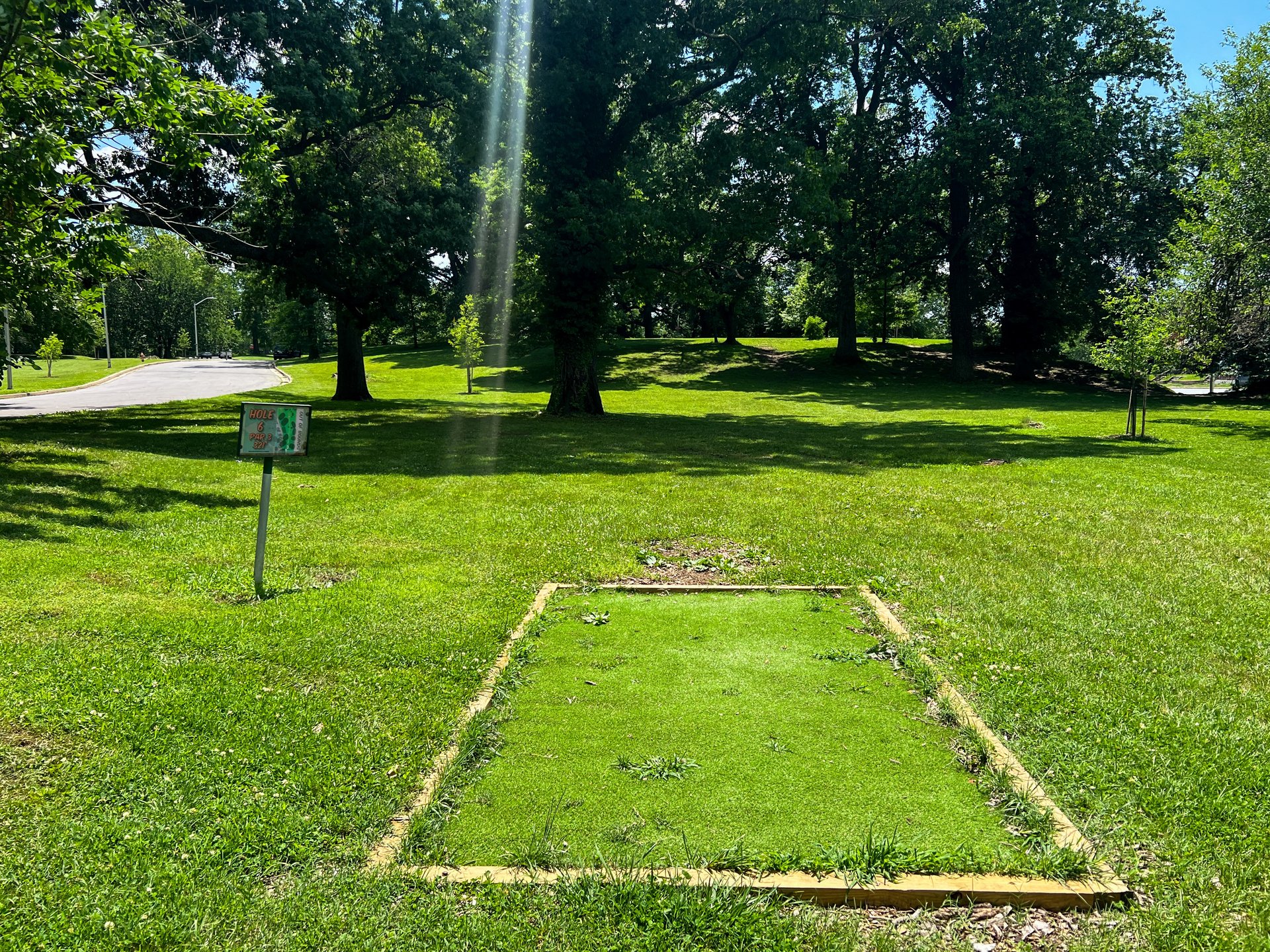 Hole 6's tee. Par 3. Pink basket is 353 ft away and is straight ahead up  the hill. Road is OB on both sides. Currently there is no Yellow Basket on Hole 6. 