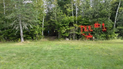 This is the first tee. It is just to the right of the entrance to the bike trails. There is a bathroom in the large building that is out of frame to the left.