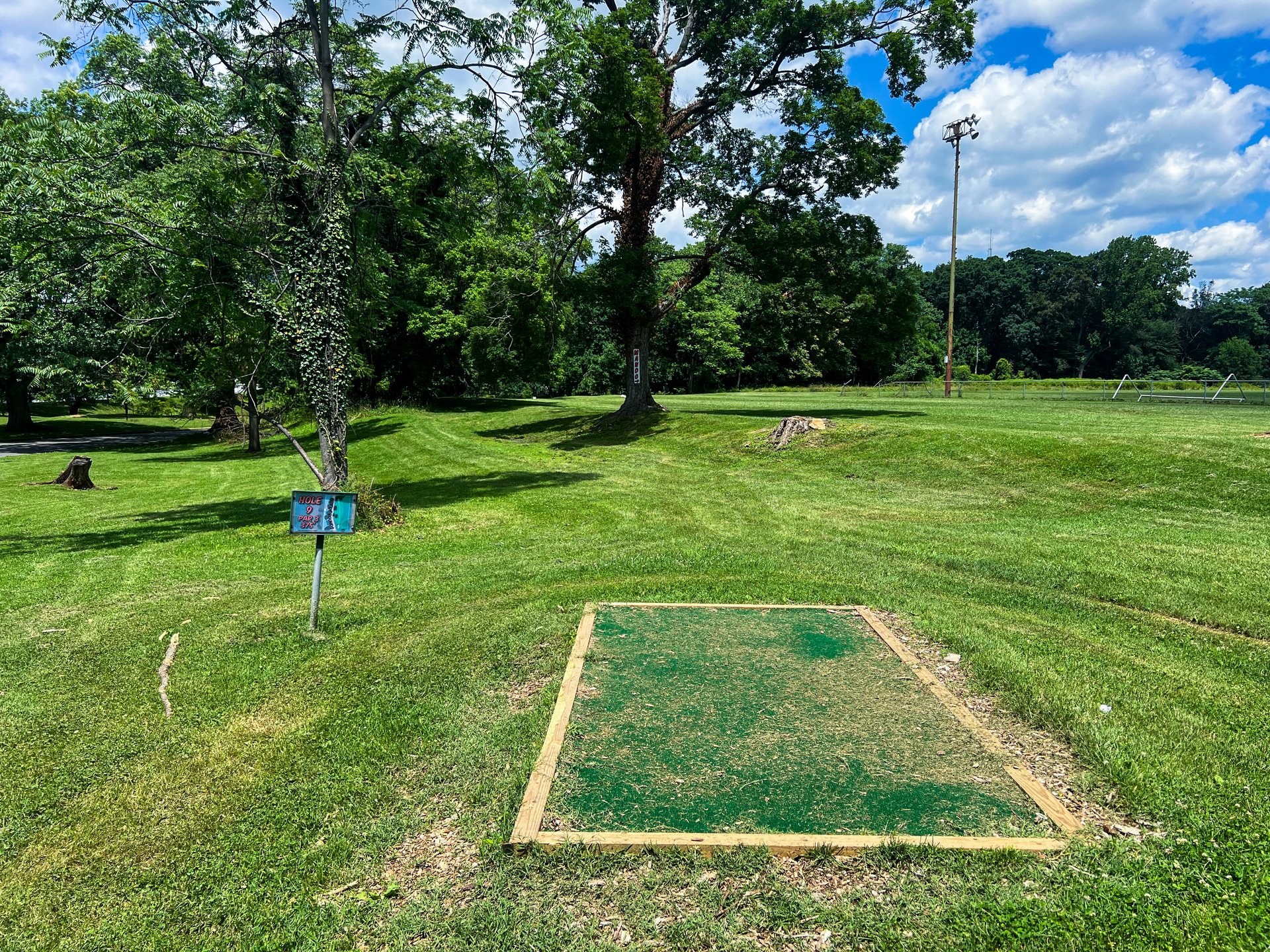 Hole 9's tee, Par 3. Have to go to the right of the MANDO.  Pink is 354 ft. Road to the left is OB. Currently there is no Yellow Basket on Hole 9. 
