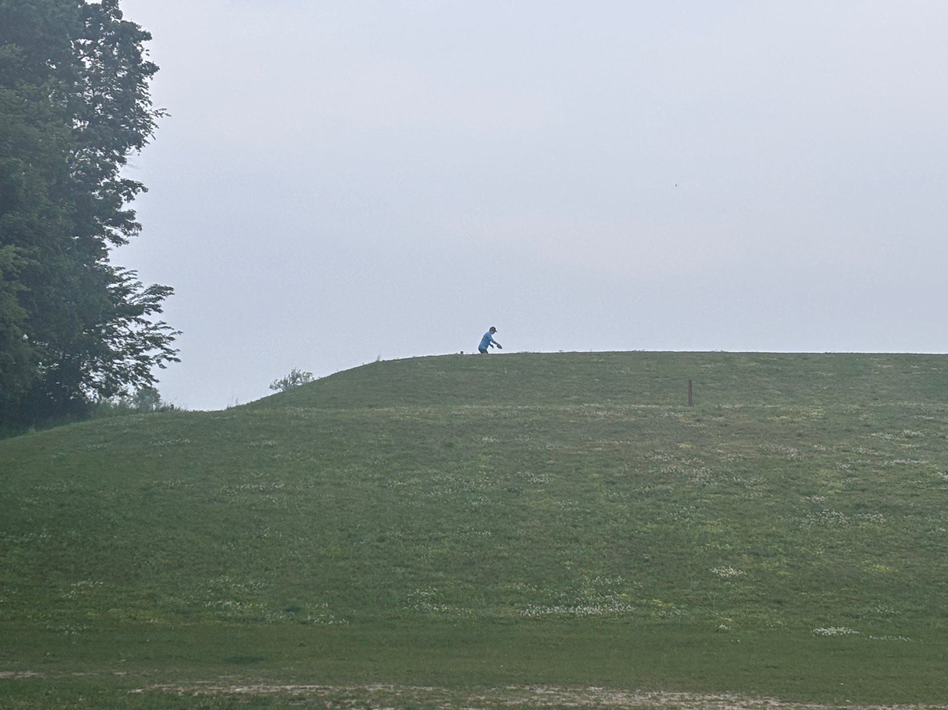 Looking back up the hill to a disc golfer at the blue tees.