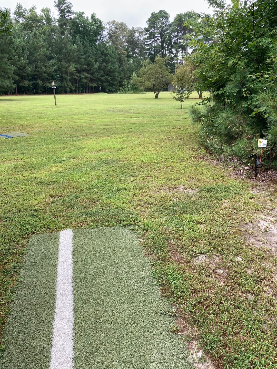3x tee pad to basket on mound , OB is brush pile 
Tee is directly in front of the clubhouse 