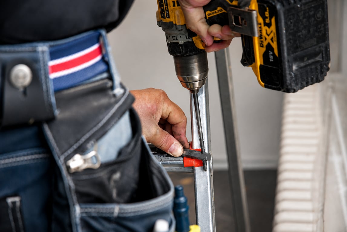 Vissage d'une fixation sur un rail en aluminium, ceinture à outils au premier plan