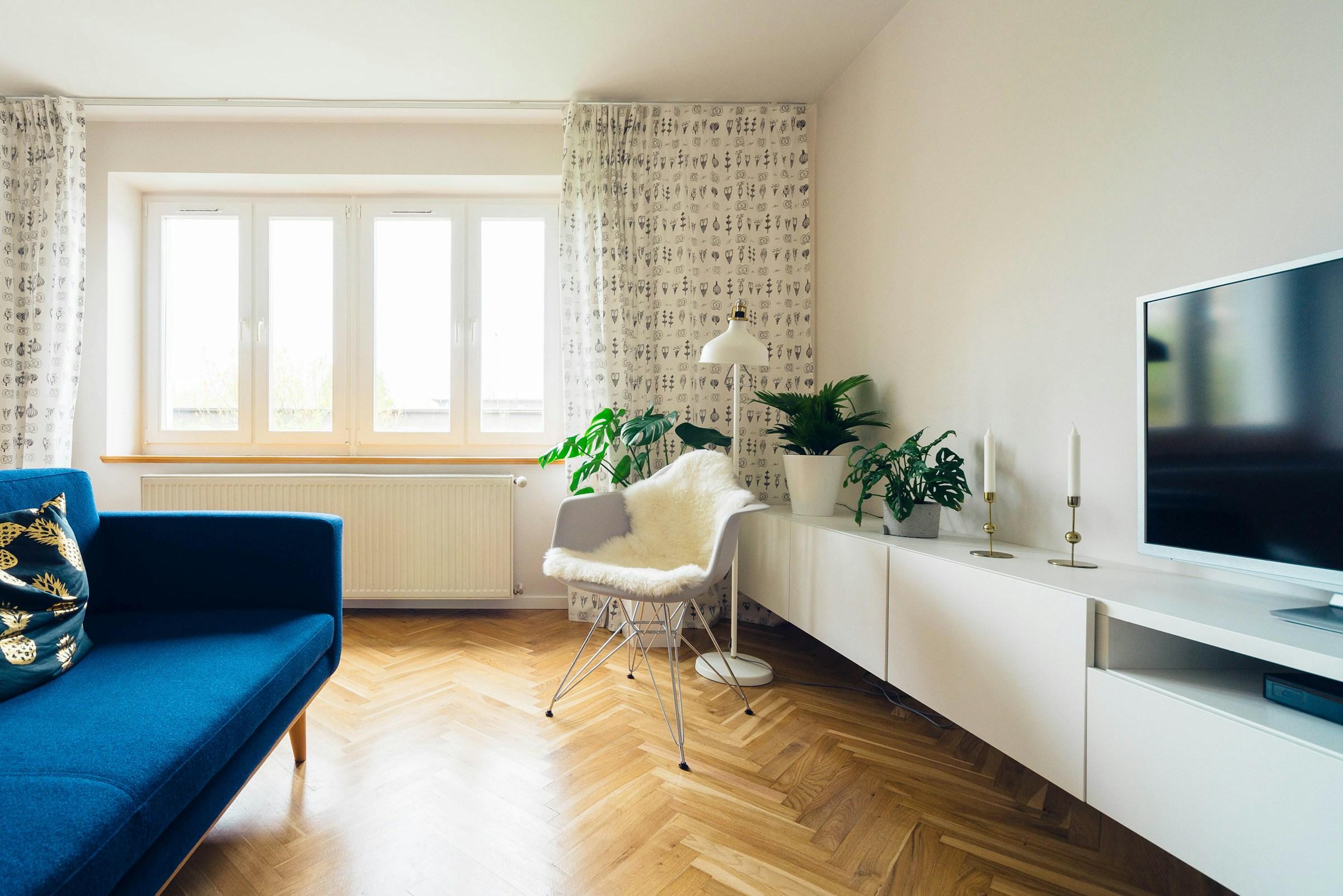 Séjour clair au parquet en point de Hongrie, canapé bleu et grandes fenêtres.