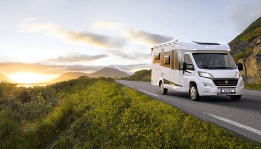 small_motorhome_driving_on_a_road_as_sun_is_rising.jpg
