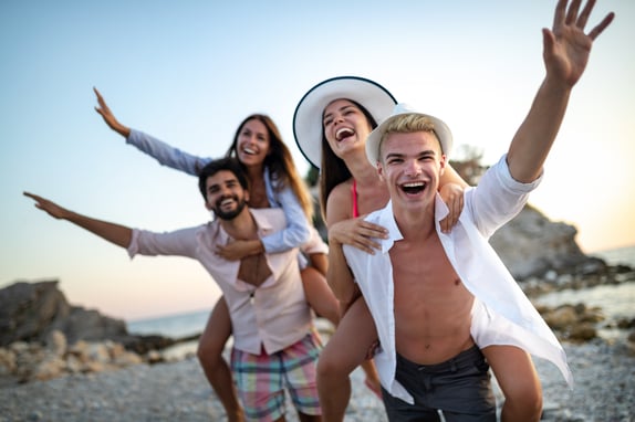 Group of friends having fun on the beach under sunset on vacation
