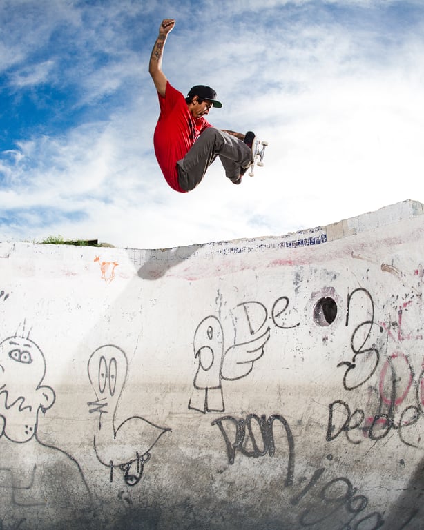 A skateboarder riding in an empty backyard pool.