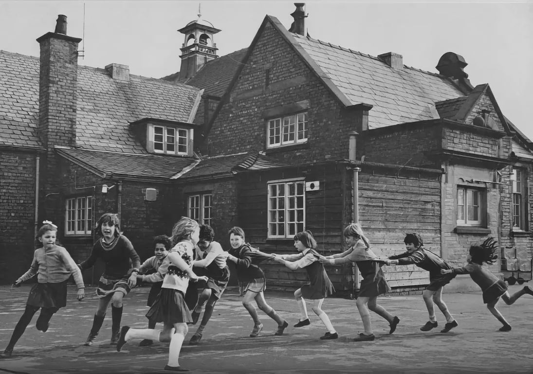 A black and white photo of children running in a playground