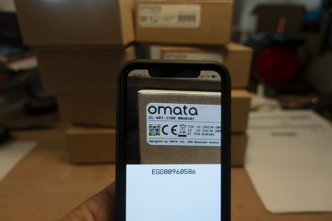 A phone reading the QR code on an OMATA box.