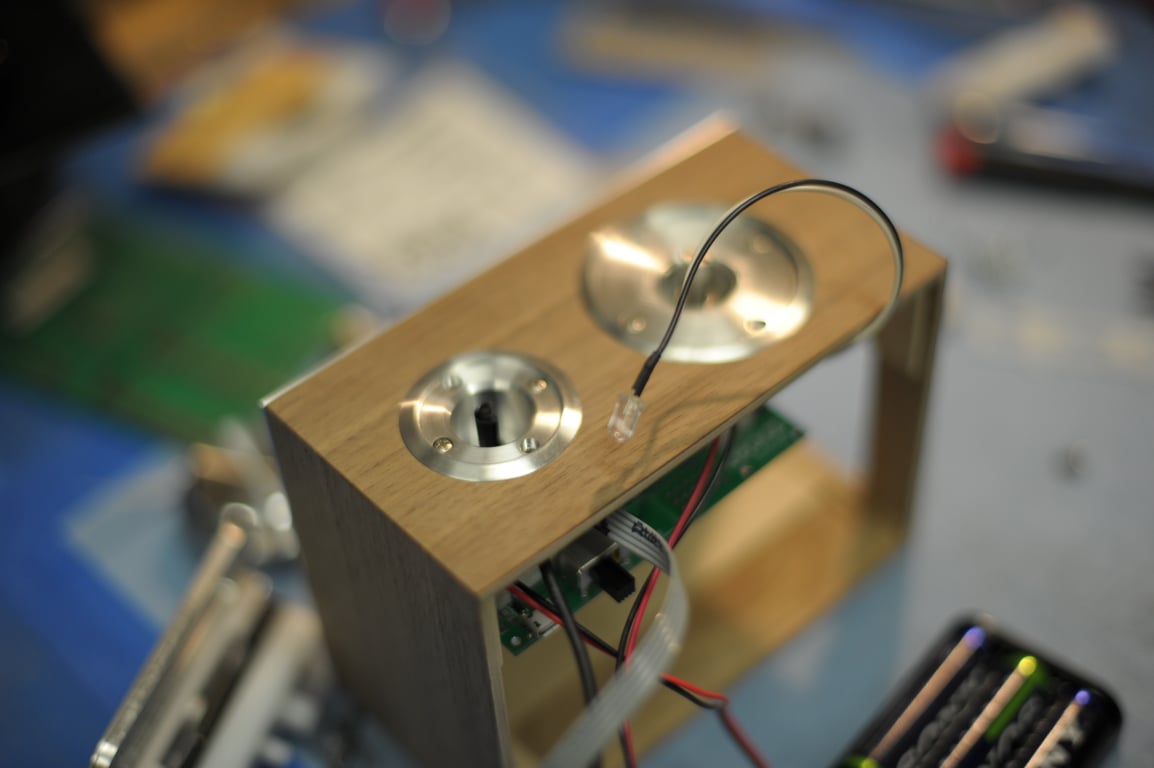 Humbo enclosure resting on its side with two circular metal control mounts, an exposed board, loose wires, and a battery holder.