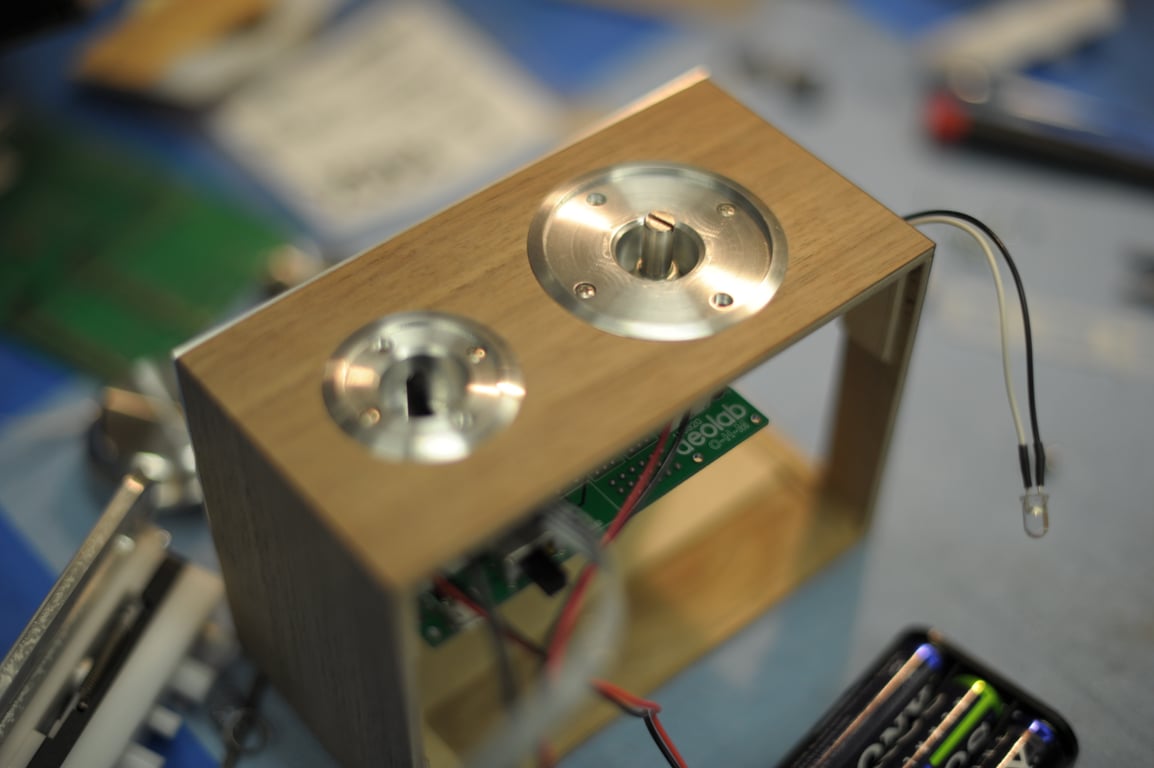 Open wooden Humbo enclosure with two circular metal control mounts, an internal circuit board, and loose wiring.