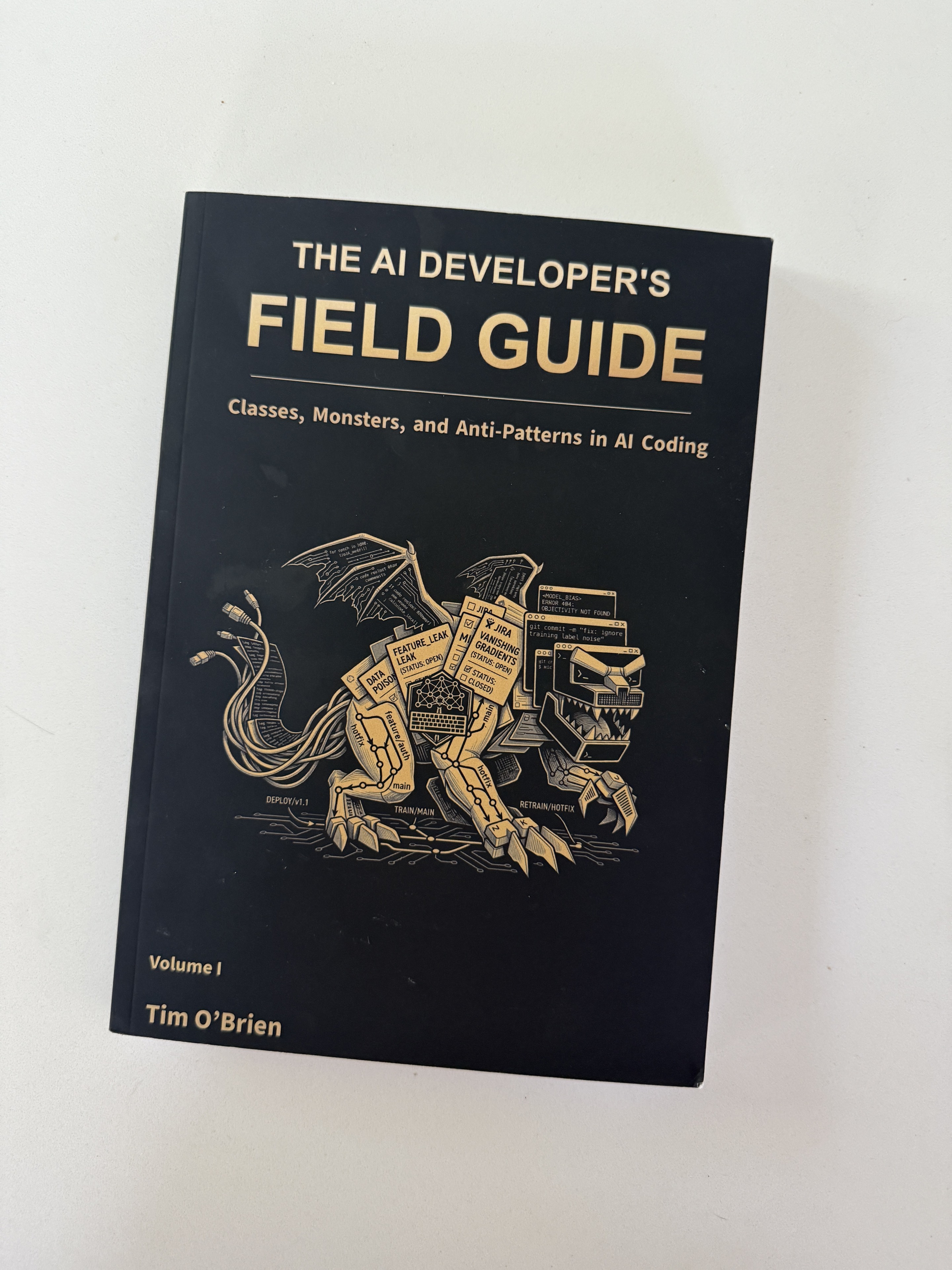 Full photograph of the black front cover of The AI Developer's Field Guide, Volume I: Classes, Monsters, and Anti-Patterns in AI Coding by Tim O'Brien, with a gold mechanical dragon illustration.