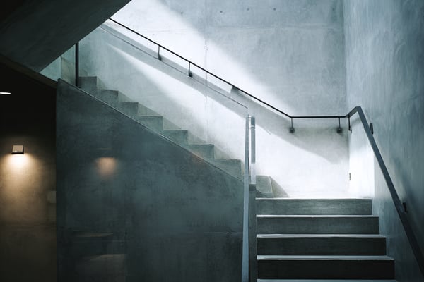 Concrete staircase with metal railings, illuminated by natural light from above.