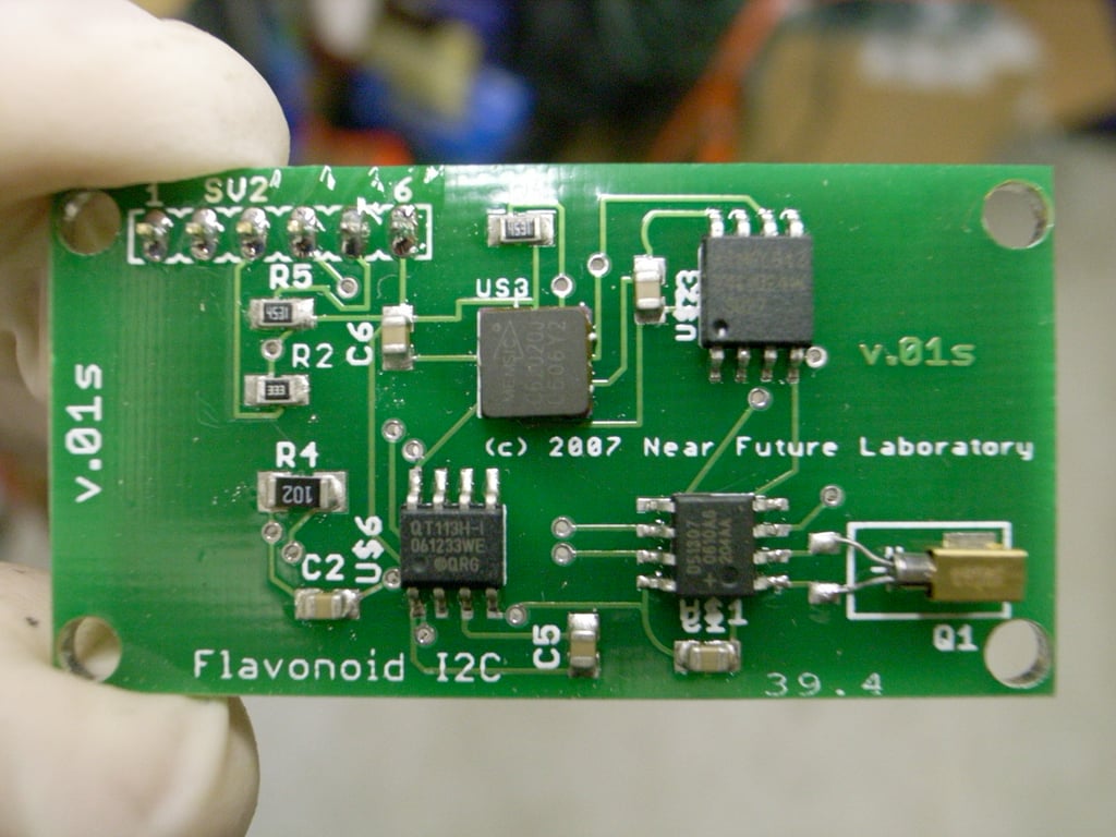 Close-up of a green Flavonoid I2C circuit board held during assembly.