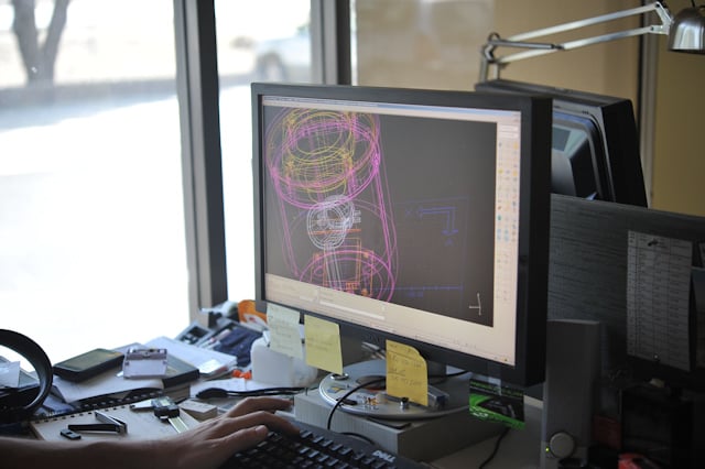 Computer monitor displaying a colorful CAD wireframe of the Social Speaker form.