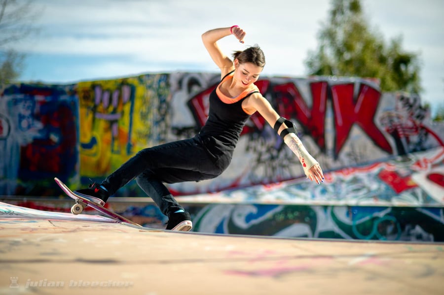 A skateboarder with a cast doing a front rock in an abandoned pool