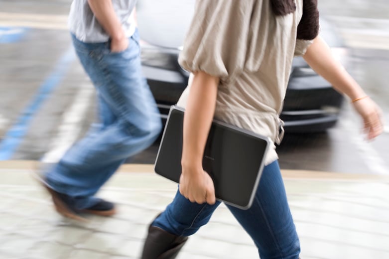 A person holding and using a handheld device while walking.