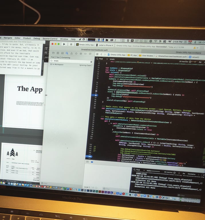 A book photograph of Xcode showing OMATA Bluetooth and overview code, with the developing app and book pages visible around the laptop.