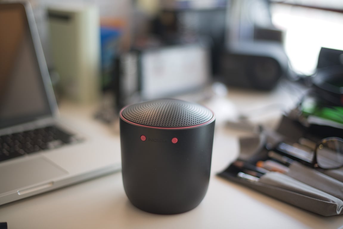 Black Social Speaker form prototype with red illuminated controls on a workbench.