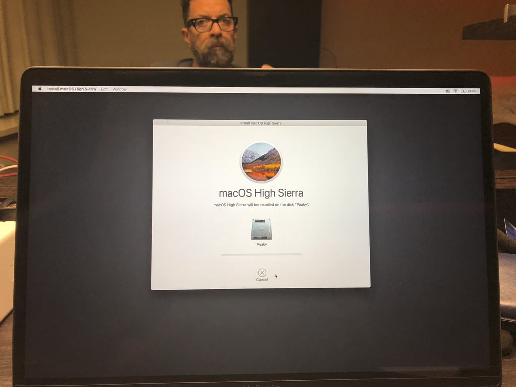 A macOS installation screen, with Julian visible behind the laptop.