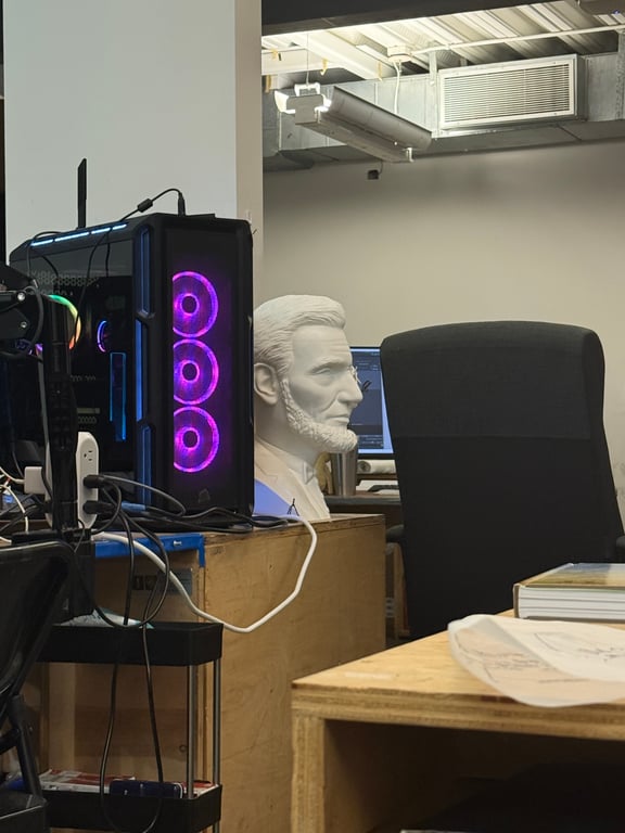 A computer tower with purple lights beside a white bust of a man in an office setting.