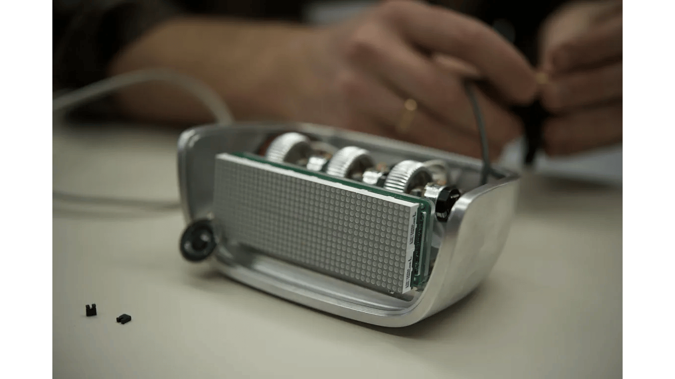 Animated views of the Social Alarm Clock prototype and hands operating its physical controls.
