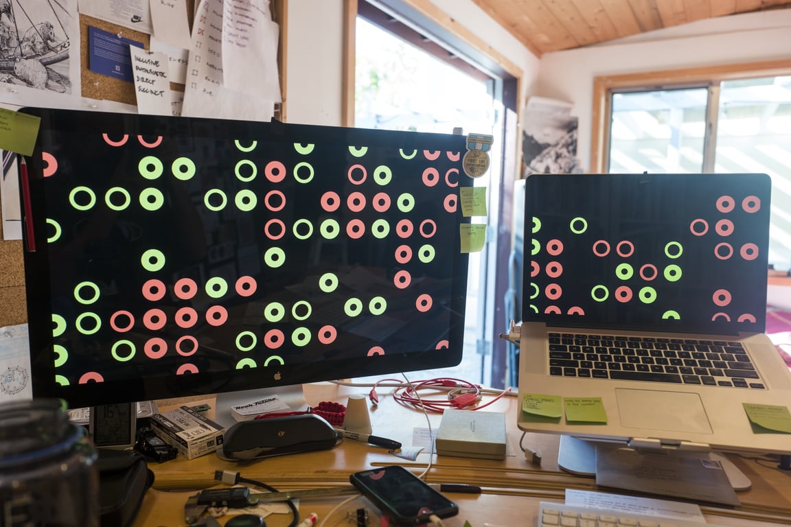 OMATA circles on the studio screens, with notes, papers and cables below.