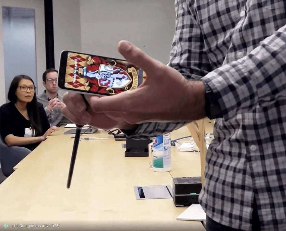 A wand and a smartphone companion screen are held above a Project Elder prototype table.