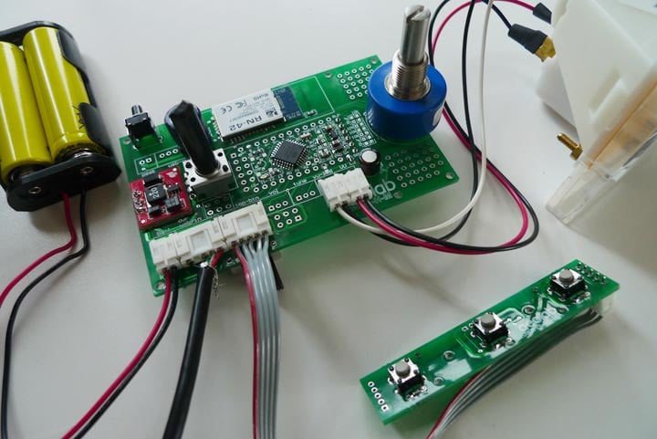 Close-up of the Humbo custom circuit board, battery pack, blue rotary control, wiring, and separate three-button switch strip.