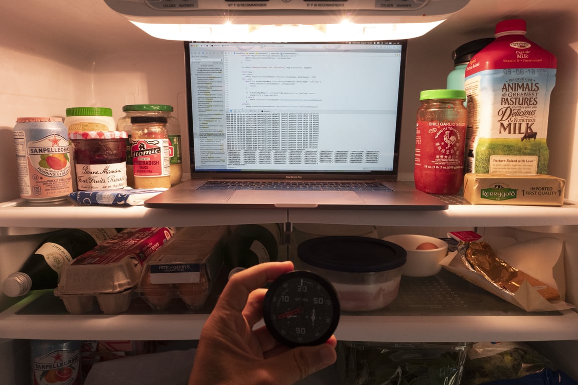 A laptop running Xcode inside the refrigerator, with an OMATA One held in front.