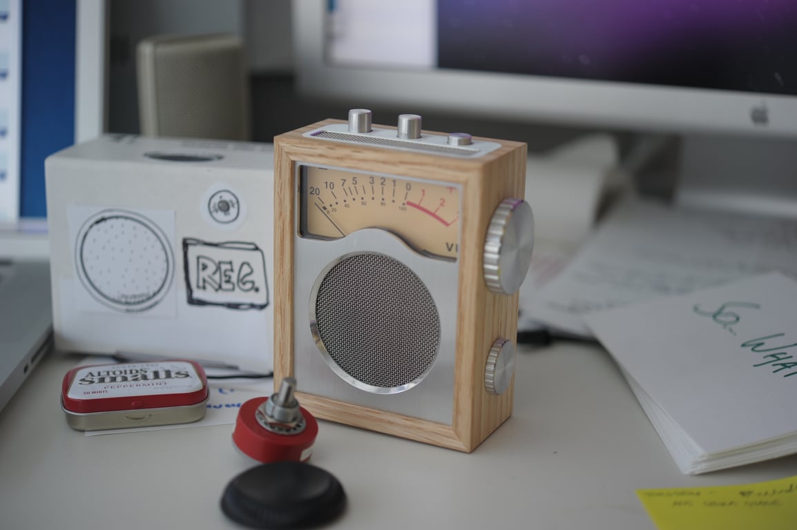 Humbo personal radio prototype in a wooden enclosure with a stainless front, analog VU meter, speaker, and side dials.