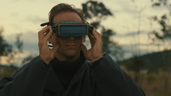 Person wearing futuristic goggles outdoors at dusk.