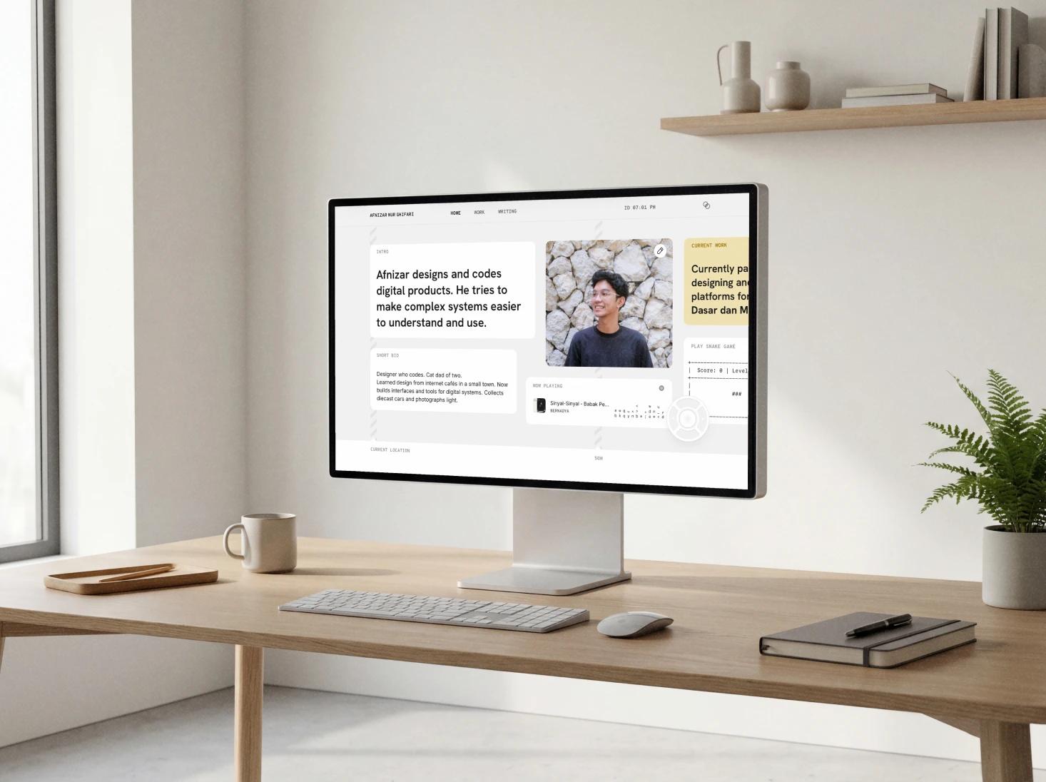 A desktop monitor on a minimalist desk displaying a personal portfolio website homepage introducing a designer and developer, with profile photo, short bio, and featured work sections.