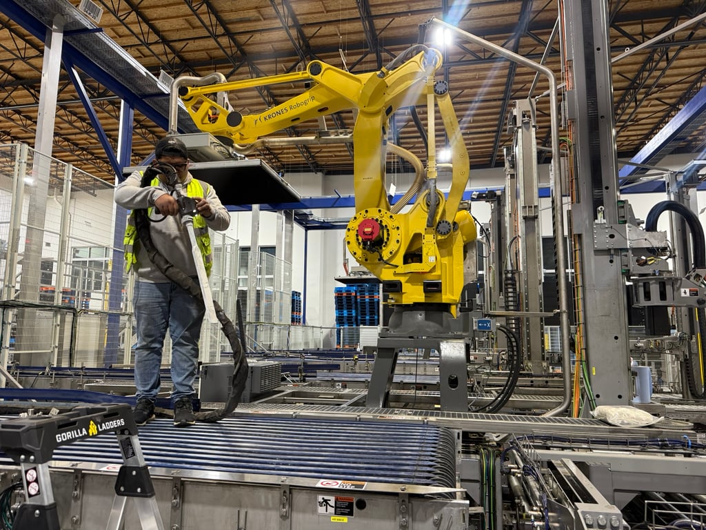 Technician cleaning a robotic arm on a packaging line, a different application requiring a different approach