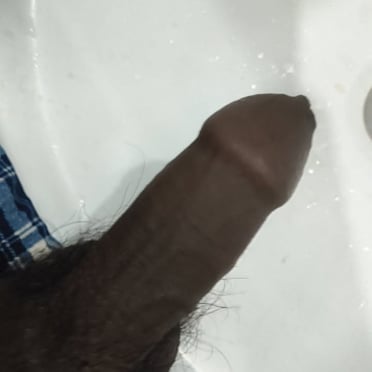 A beautiful, thick, dark cock with some bushy pubic hair is displayed in this photo.