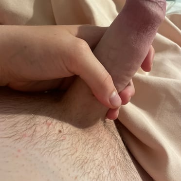 A thick, veiny cock with lightly bushy pubic hair is shown in this up-close pic.